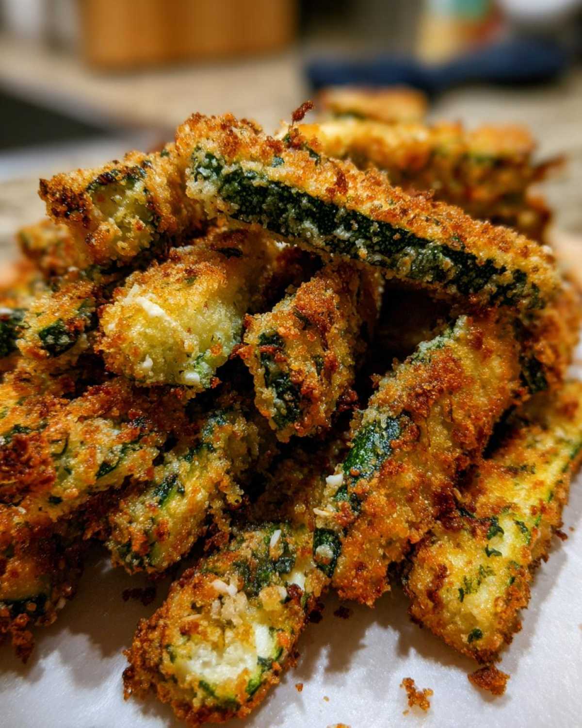 A close-up stack of golden brown, crispy Air Fryer Zucchini Fries with Parmesan coating.