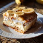 A decadent slice of Banana Pudding Cheesecake Bars topped with creamy layers and fresh banana slices.
