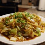 A close-up of a serving of Cabbage Stir Fry with Garlic Ginger Sauce, topped with fresh green onions.