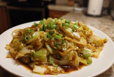 A close-up of a serving of Cabbage Stir Fry with Garlic Ginger Sauce, topped with fresh green onions.