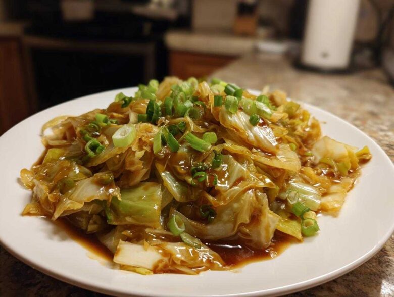 A close-up of a serving of Cabbage Stir Fry with Garlic Ginger Sauce, topped with fresh green onions.