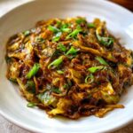 A close-up, tasty shot of Cabbage Stir Fry with Garlic Ginger Sauce, garnished with fresh green onions.