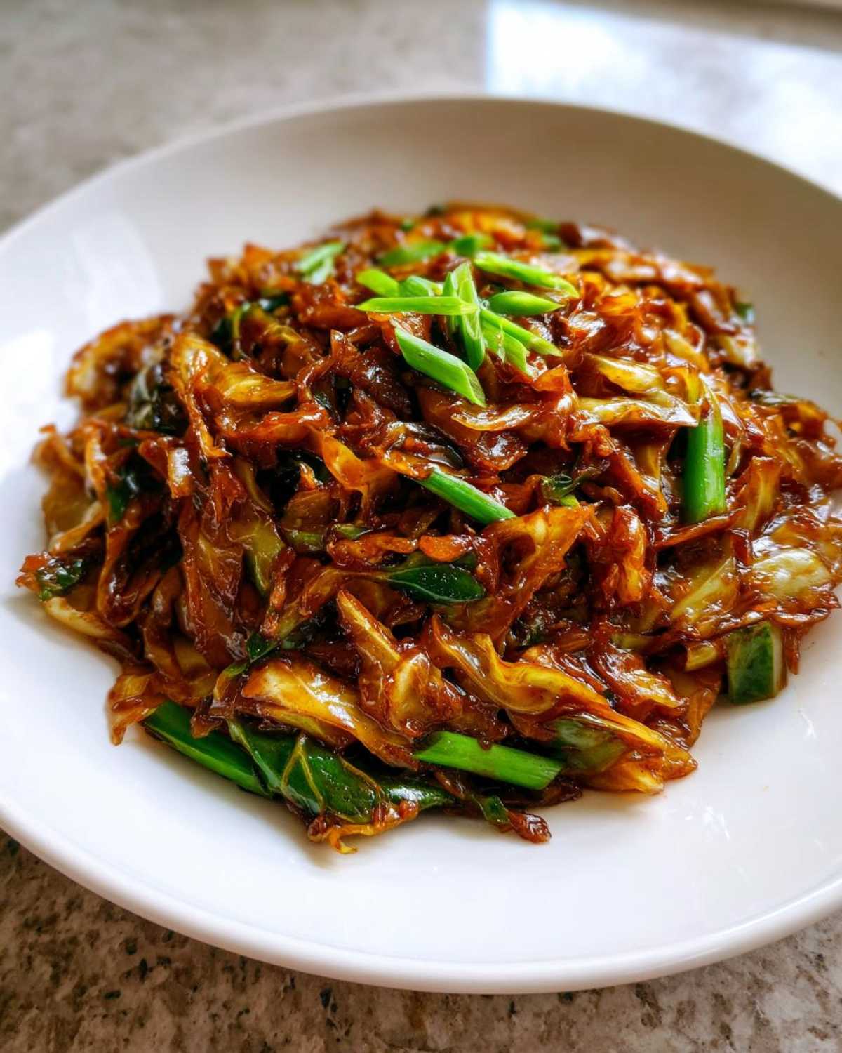 A close-up of savory Cabbage Stir Fry with Garlic Ginger Sauce, garnished with fresh green onions.