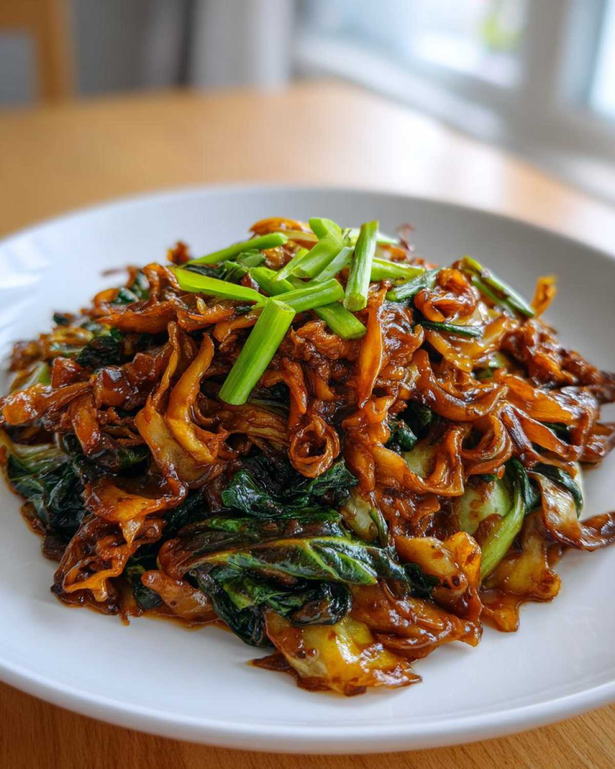 A close-up of Cabbage Stir Fry with Garlic Ginger Sauce served on a white plate, topped with fresh scallions.