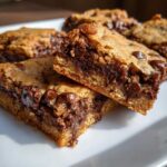 Two stacked Chewy Chocolate Chip Cookie Bars showing a gooey, melted chocolate center and golden edges.