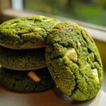 Close-up of a stack of vibrant green Chewy Matcha White Chocolate Cookies with visible white chocolate chunks.