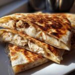 Close-up of stacked, grilled quesadilla wedges filled with shredded chicken and melted cheese, implying the use of Copycat Taco Bell Chicken Quesadilla Sauce.