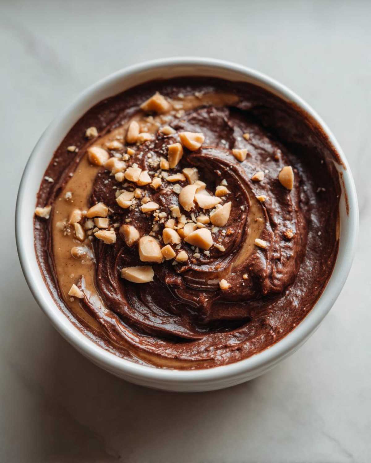 Overhead view of rich Chocolate Peanut Butter Cheesecake Dip swirled with peanut butter and topped with chopped peanuts.