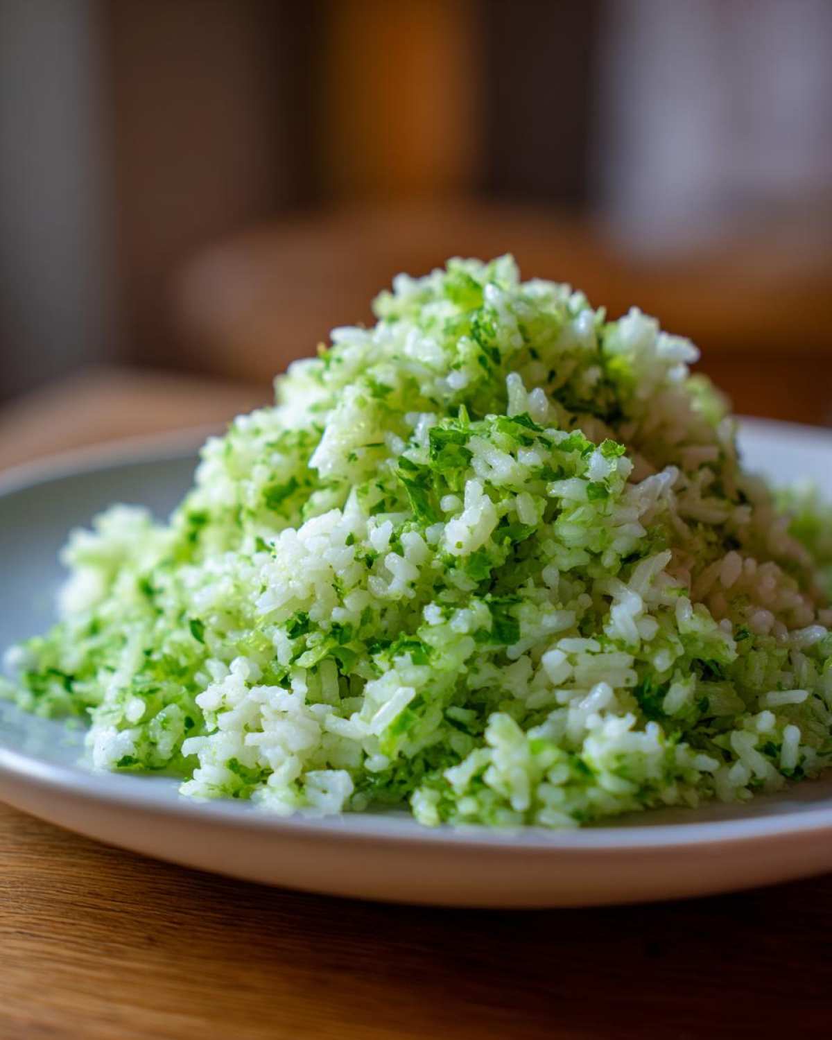 A mound of fluffy Cilantro Lime Rice, bright green from fresh herbs, served on a light gray plate.