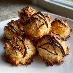 A pile of golden brown Coconut Macaroons with Dark Chocolate Drizzle on a white plate.