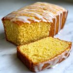 A moist slice cut from a Copycat Starbucks Iced Lemon Loaf, drizzled with white lemon icing.