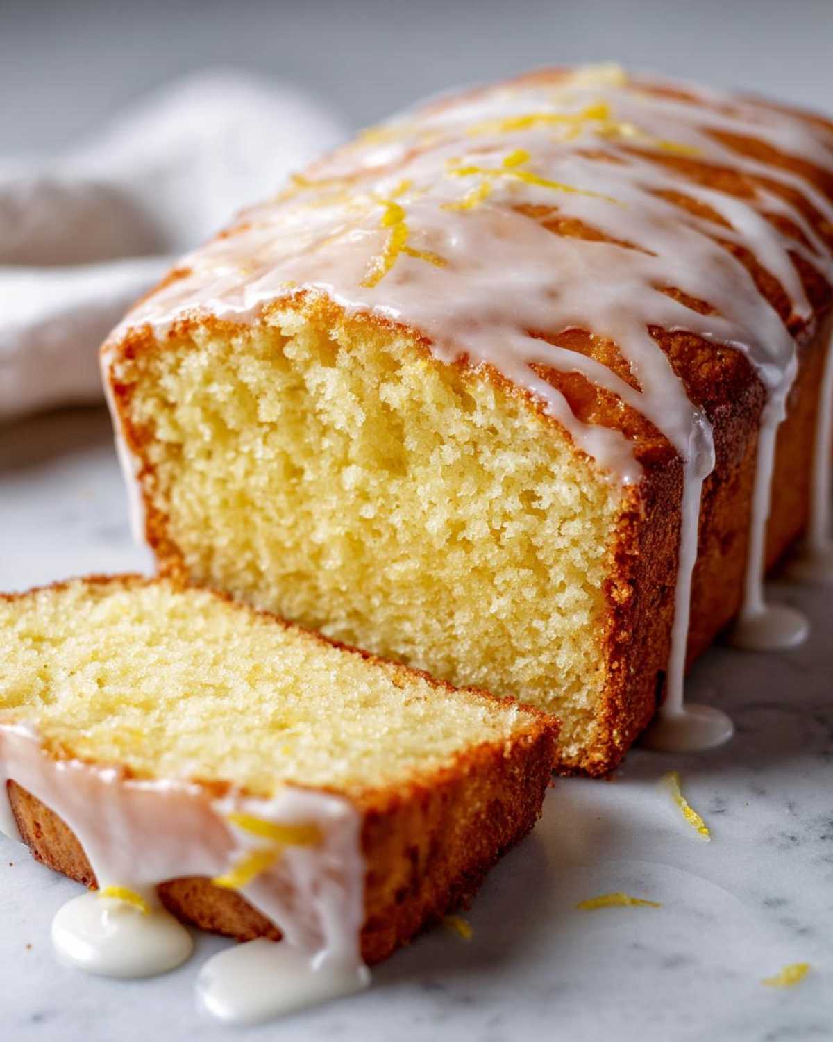 A moist slice cut from the Copycat Starbucks Iced Lemon Loaf, drizzled with thick white lemon glaze.