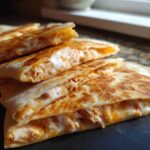 Close-up of stacked, grilled chicken quesadilla wedges oozing with melted cheese and Copycat Taco Bell Chicken Quesadilla Sauce.
