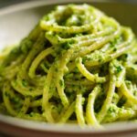 A close-up, vibrant shot of spaghetti coated thickly in bright green Creamy Avocado Pasta sauce.