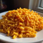 A generous serving of creamy, bright orange Instant Pot Mac and Cheese piled high on a white plate.