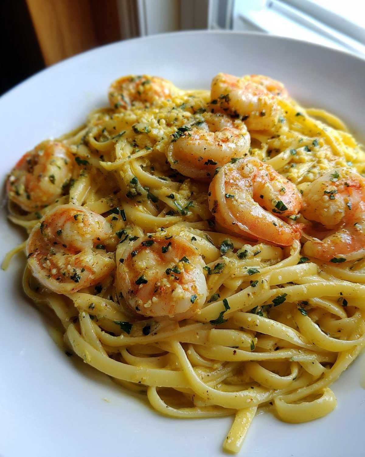 Close-up of Creamy Lemon Garlic Shrimp Pasta featuring plump shrimp over fettuccine noodles coated in a rich sauce.
