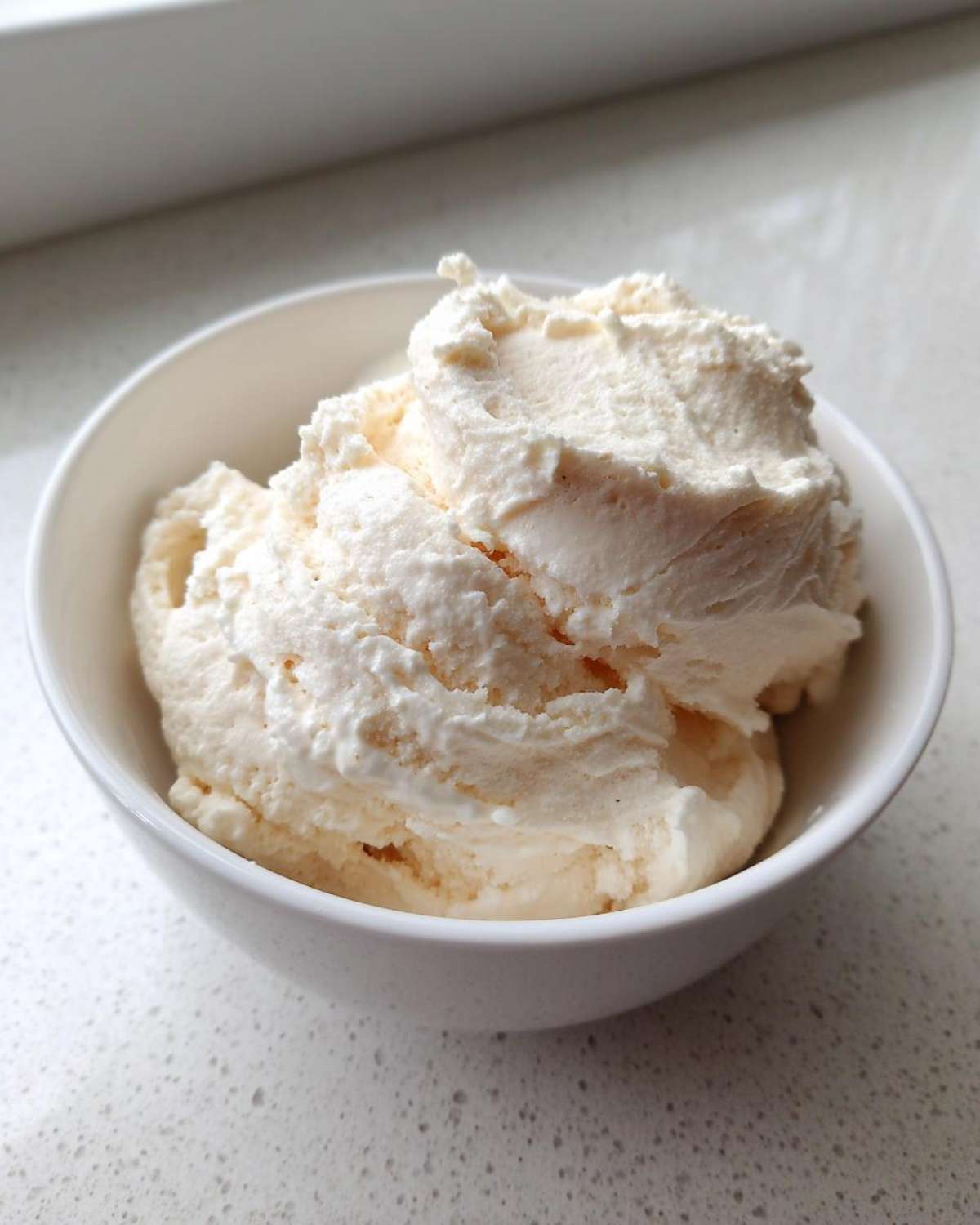 Close-up of thick, creamy vanilla protein smoothie bowl base scooped into a white bowl.