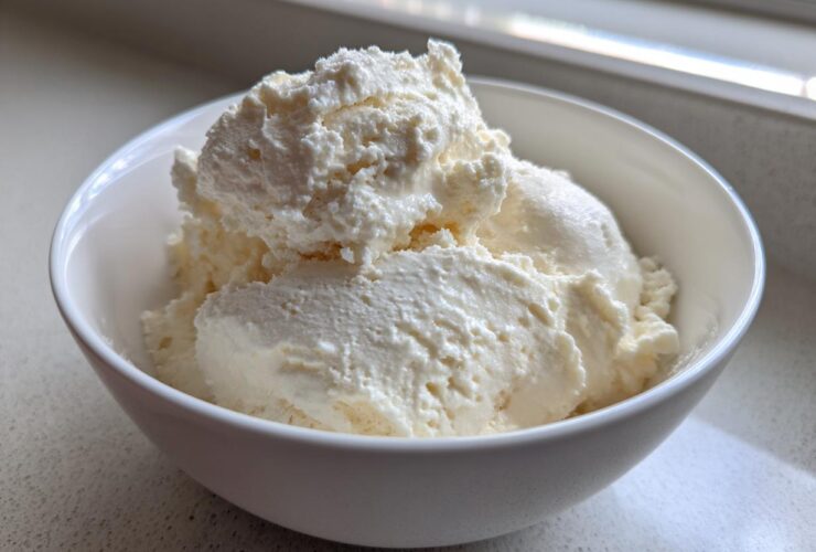 A white bowl filled with thick, creamy vanilla protein smoothie bowl mixture, resembling soft-serve ice cream.