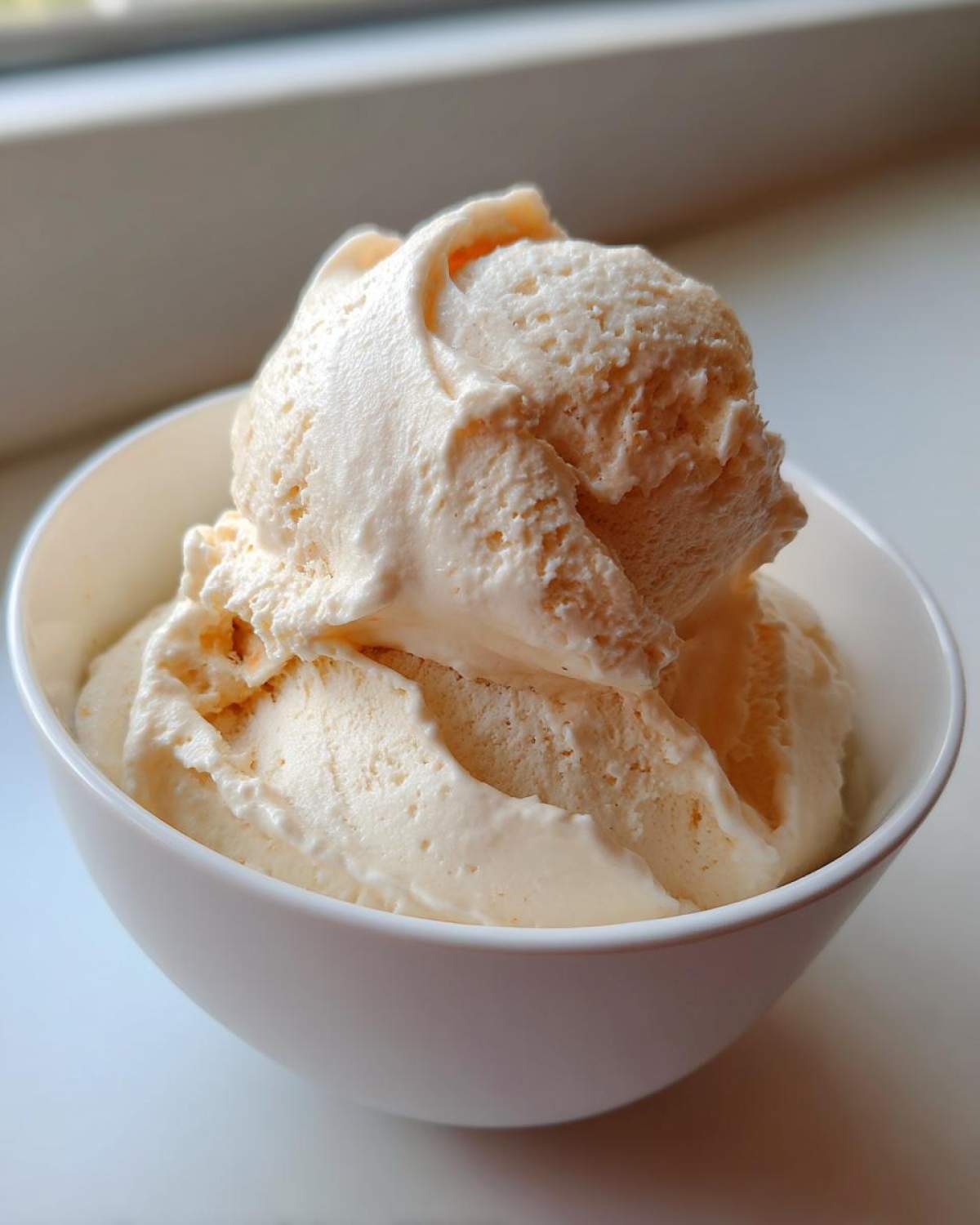 Close-up of thick, creamy scoops of vanilla mixture resembling ice cream in a white bowl, representing the Creamy Vanilla Protein Smoothie Bowl.