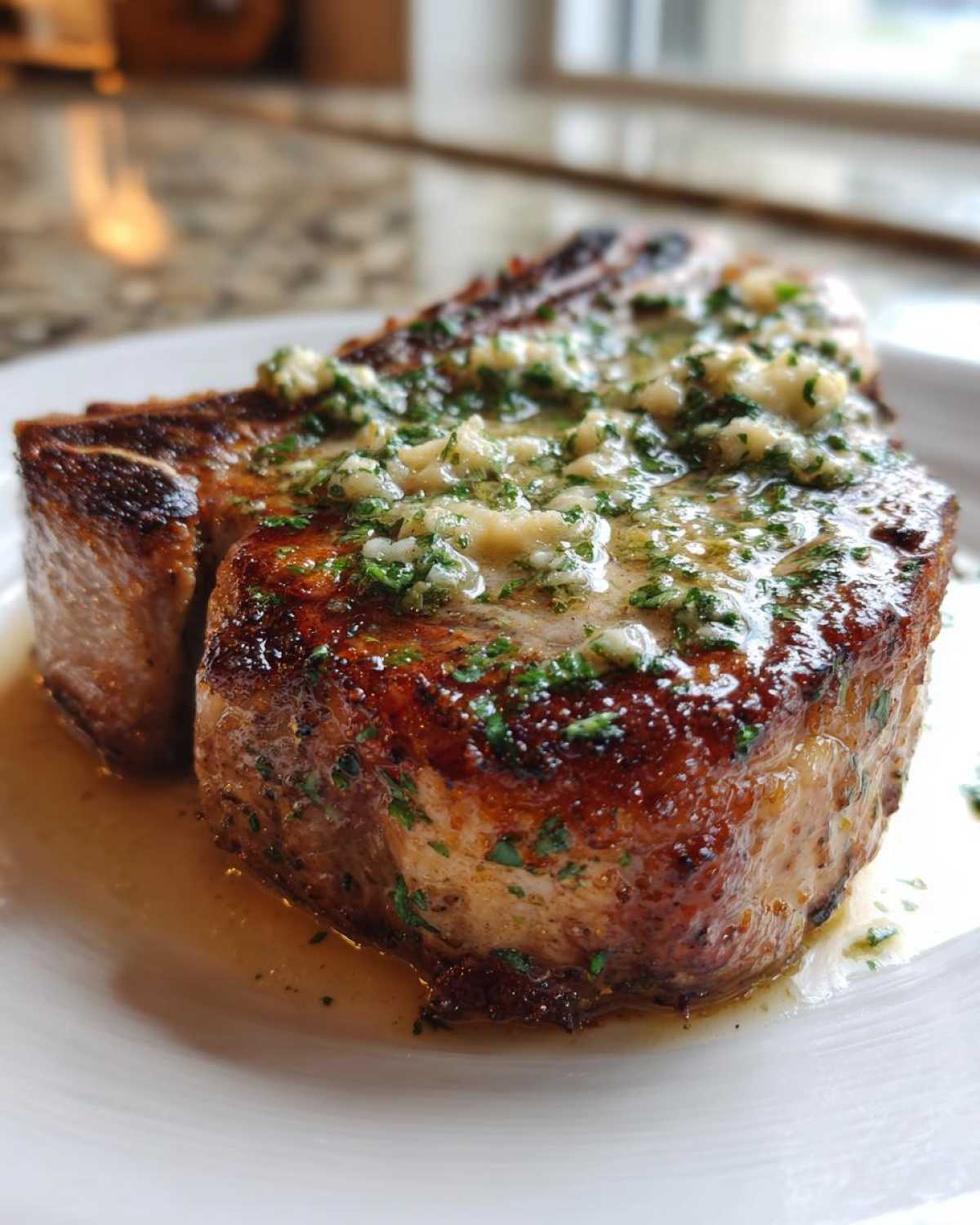 A thick, bone-in Crispy Air Fryer Pork Chop smothered in melted garlic butter and parsley.