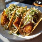 Three Crispy Baked Fish Tacos filled with breaded white fish and topped generously with bright lime slaw.