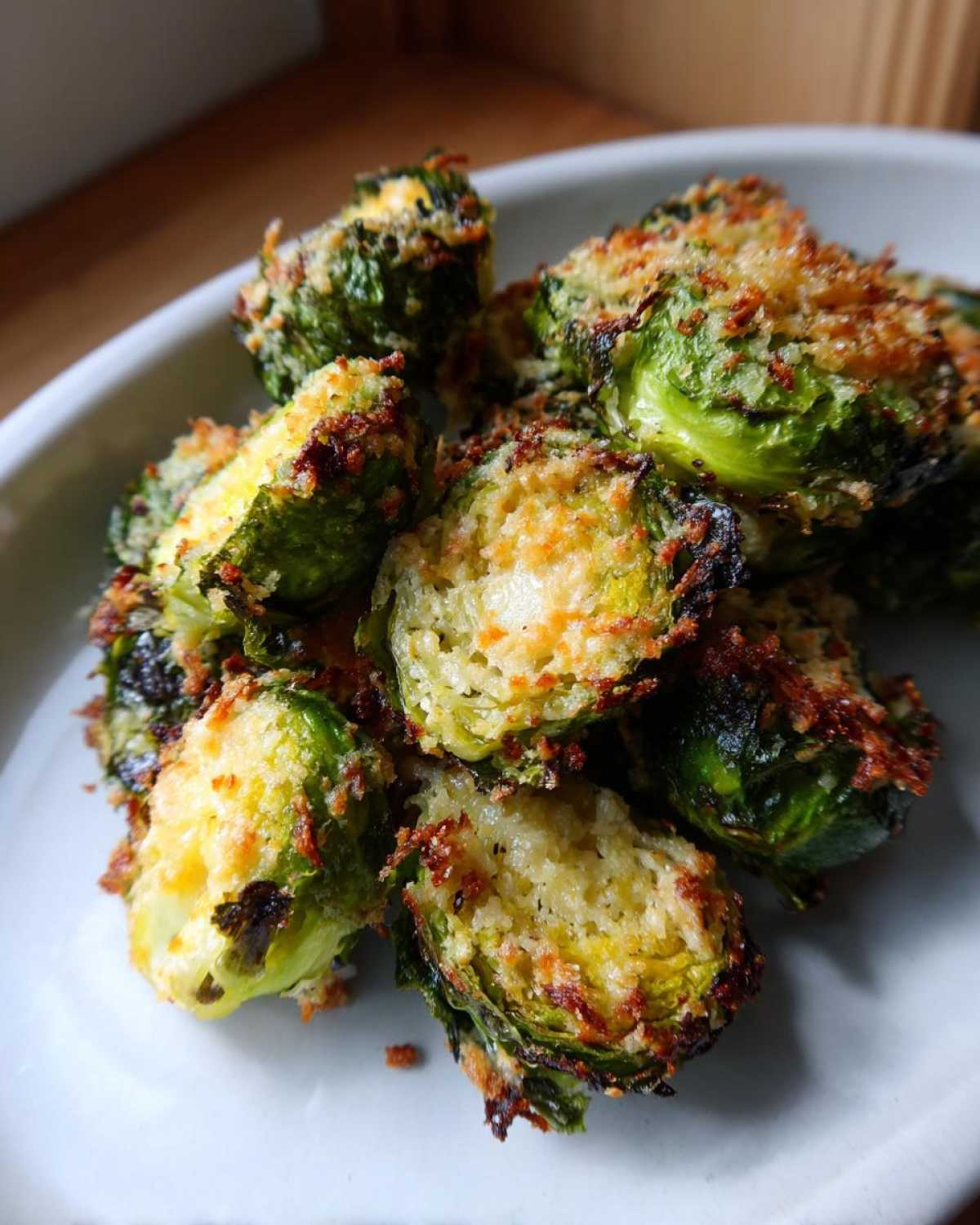 Close-up of perfectly roasted Crispy Parmesan Brussels Sprouts, halved and topped with golden brown cheese.