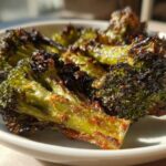 Close-up of perfectly charred and crispy Parmesan roasted broccoli florets served in a white bowl.