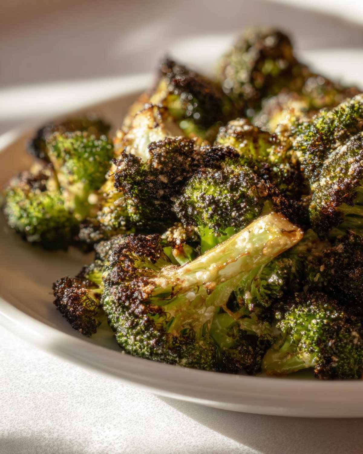 Close-up of deeply roasted, Crispy Parmesan Roasted Broccoli florets with charred edges and grated cheese.