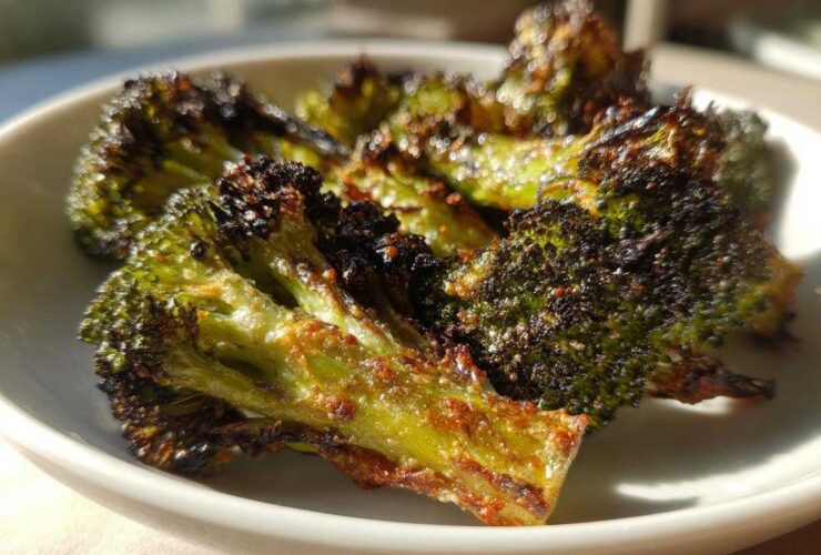 Close-up of perfectly charred and crispy Parmesan roasted broccoli florets served in a white bowl.