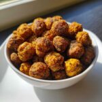 Close-up of a white bowl filled with golden brown, seasoned Crunchy Air Fryer Ranch Chickpeas.