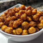 A close-up of a white bowl filled with golden, seasoned Crunchy Air Fryer Ranch Chickpeas.