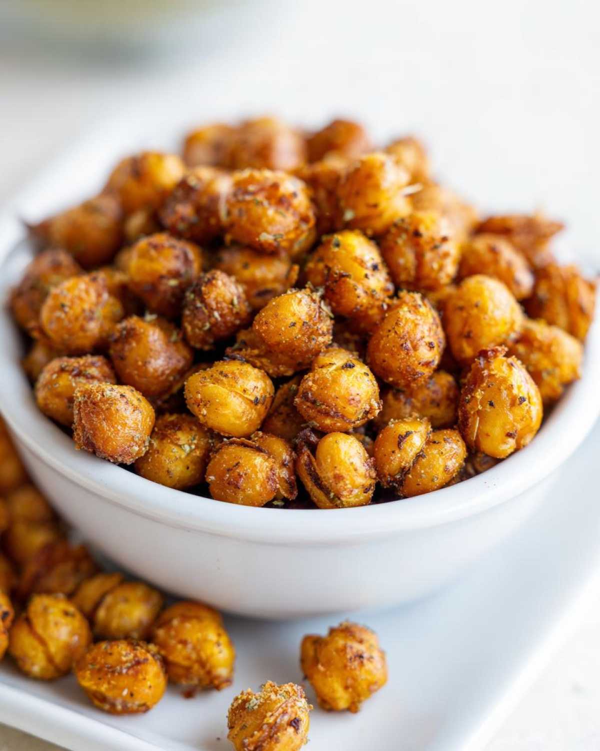 Close-up of a white bowl filled with golden brown, seasoned Crunchy Air Fryer Ranch Chickpeas.
