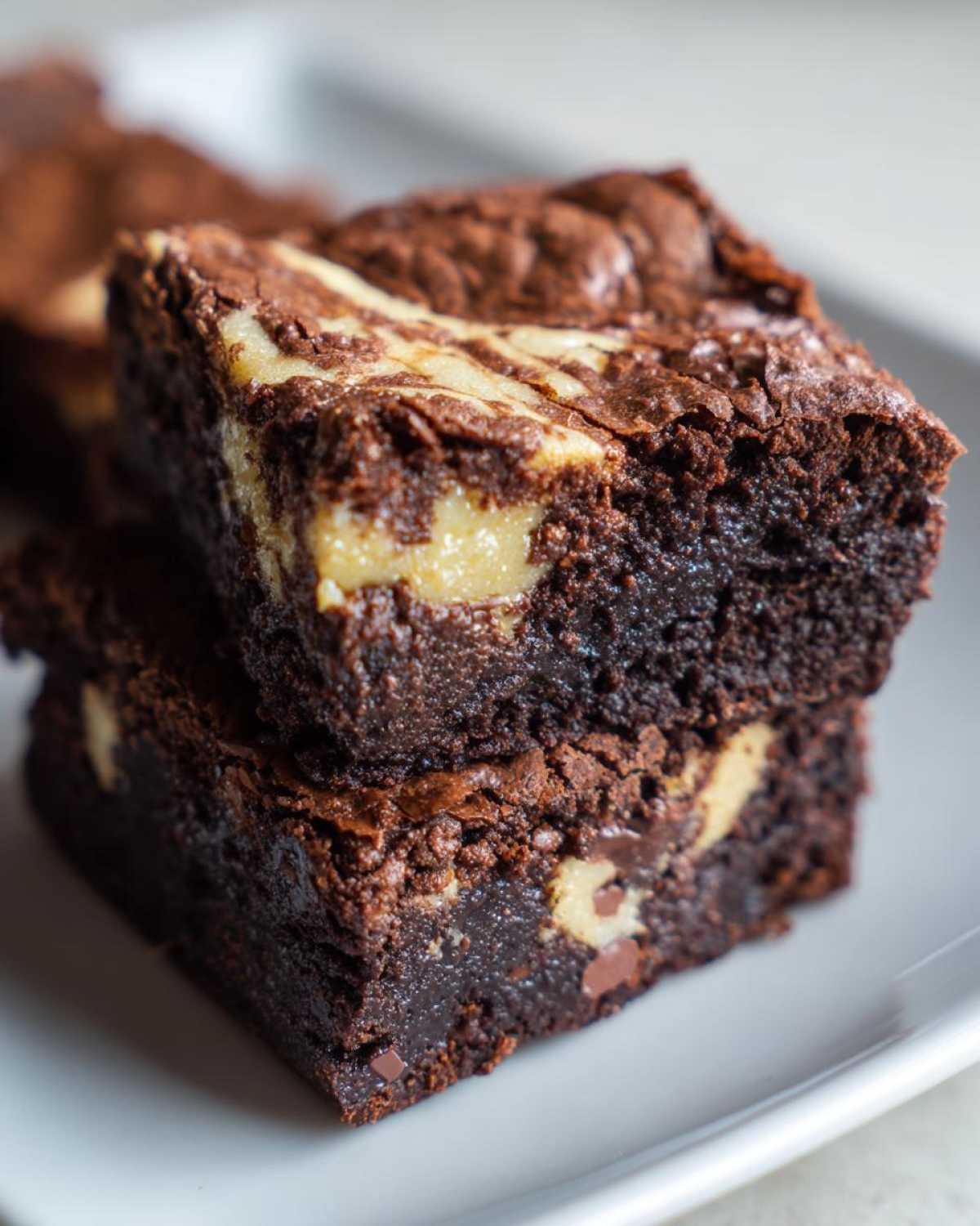 Close-up of two stacked, fudgy Dark Chocolate Tahini Brownies featuring a visible tahini swirl.