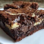 Close-up of a moist Dark Chocolate Tahini Brownies square with a visible tahini swirl and melted chocolate chunks.