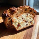 A loaf of Easy Irish Soda Bread with Buttermilk and Raisins, sliced open to show the soft interior and fruit.
