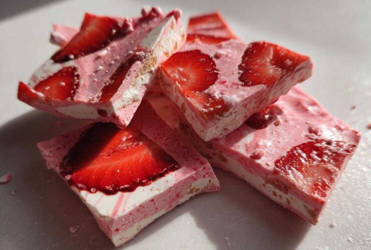 Close-up of broken pieces of Frozen Strawberry Yogurt Bark, showing layers of pink yogurt and fresh strawberry slices.