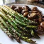A plate featuring vibrant green Garlic Butter Roasted Asparagus and browned, savory roasted mushrooms.