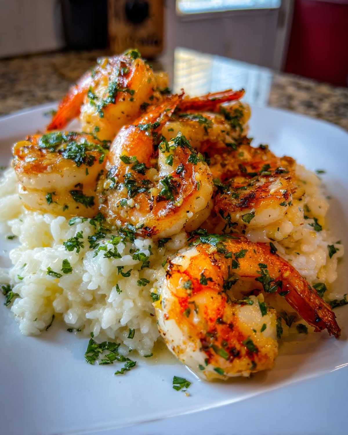 Close-up of perfectly cooked Garlic Butter Shrimp served over white rice and garnished with parsley.