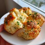 A hand pulling apart warm Garlic Parmesan Pull-Apart Bread, showing melted cheese strings and parsley garnish.