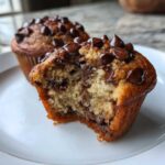 Close-up of a Gluten-Free Banana Chocolate Chip Muffin with a bite taken out, showing moist interior and melted chocolate chips.
