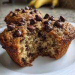 Close-up of a Gluten-Free Banana Chocolate Chip Muffin with a bite taken out, showing moist texture and chocolate chips.