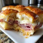Close-up of Hawaiian Roll Ham and Cheese Sliders cut in half, showing melted cheese dripping over ham.