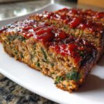 Close-up of a thick slice of Healthy Turkey Spinach Meatloaf topped with a shiny red glaze.