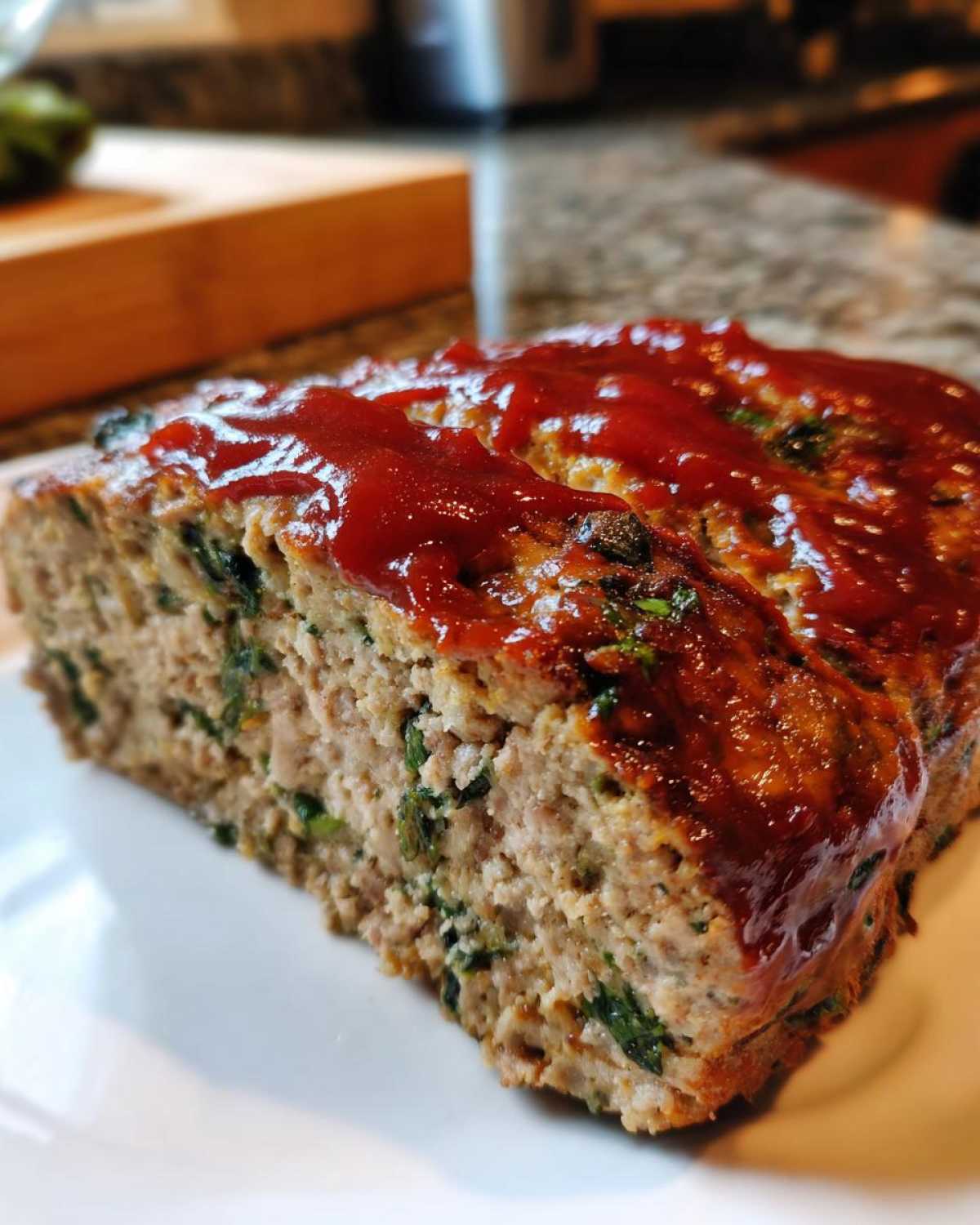 Close-up of a thick slice of Healthy Turkey Spinach Meatloaf topped with a shiny red glaze.