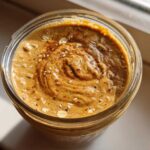 Overhead view of thick High-Protein Peanut Butter Overnight Oats topped with oats and cinnamon in a glass jar.