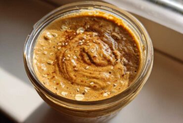 Overhead view of thick High-Protein Peanut Butter Overnight Oats topped with oats and cinnamon in a glass jar.