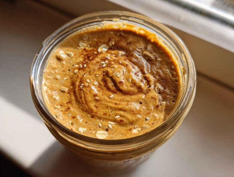 Overhead view of thick High-Protein Peanut Butter Overnight Oats topped with oats and cinnamon in a glass jar.