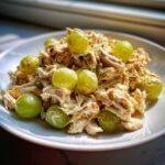 A mound of creamy Honey Mustard Chicken Salad with Grapes served on a white plate.
