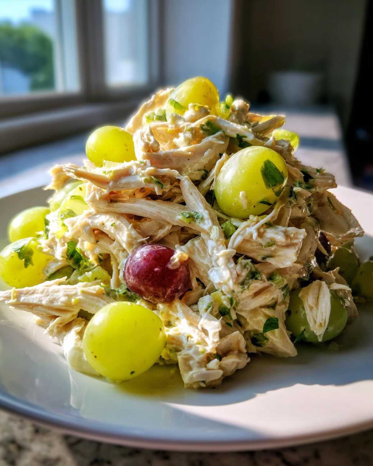 A mound of creamy Honey Mustard Chicken Salad with Grapes, featuring shredded chicken and whole green and red grapes.