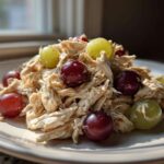 Close-up of shredded Honey Mustard Chicken Salad with Grapes on a light plate.